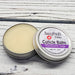A cuticle balm open with a metal lid, showing a solid yellow cuticle balm inside, placed on a wooden surface.  Blackberry Sage