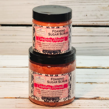 Two jars of Cranberry Almond Foaming Sugar Scrub stacked on a wooden surface.