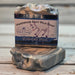 Handmade goat milk soap bar with a label by Handmade Natural Beauty on a wooden surface