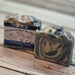 Handmade goat milk soap bar with a label by Handmade Natural Beauty on a wooden surface