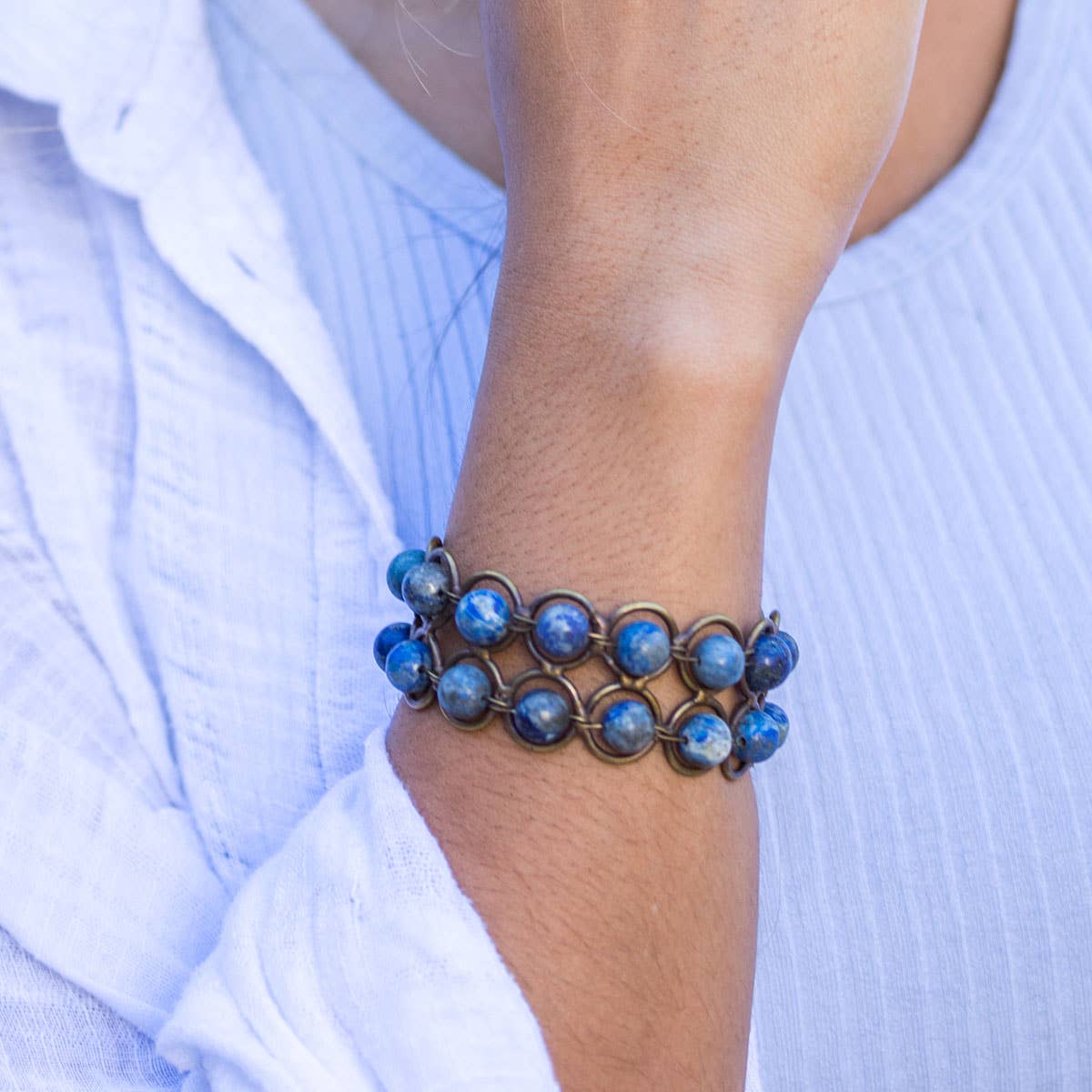 a woman wearing An adjustable wire-wrapped bracelet with lapis lazuli beads and antique brass clasps.