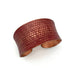 Copper cuff bracelet with textured pattern on a white background