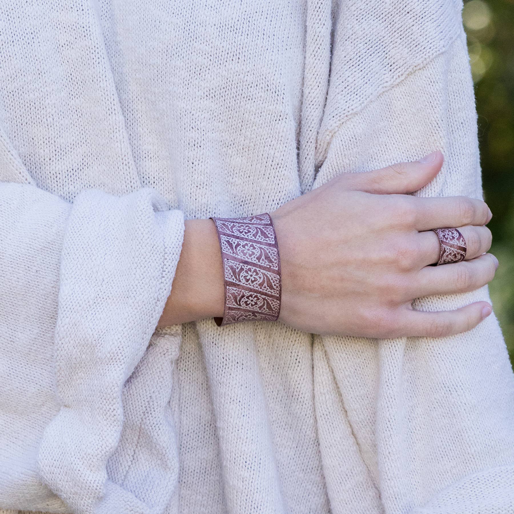 Person wearing a textured bracelet and ring on a neutral background