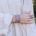 Person wearing a textured bracelet and ring on a neutral background