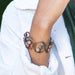 a woman wearing An adjustable wire-wrapped cuff bracelet with multicolored stone beads and a antique brass finish.
