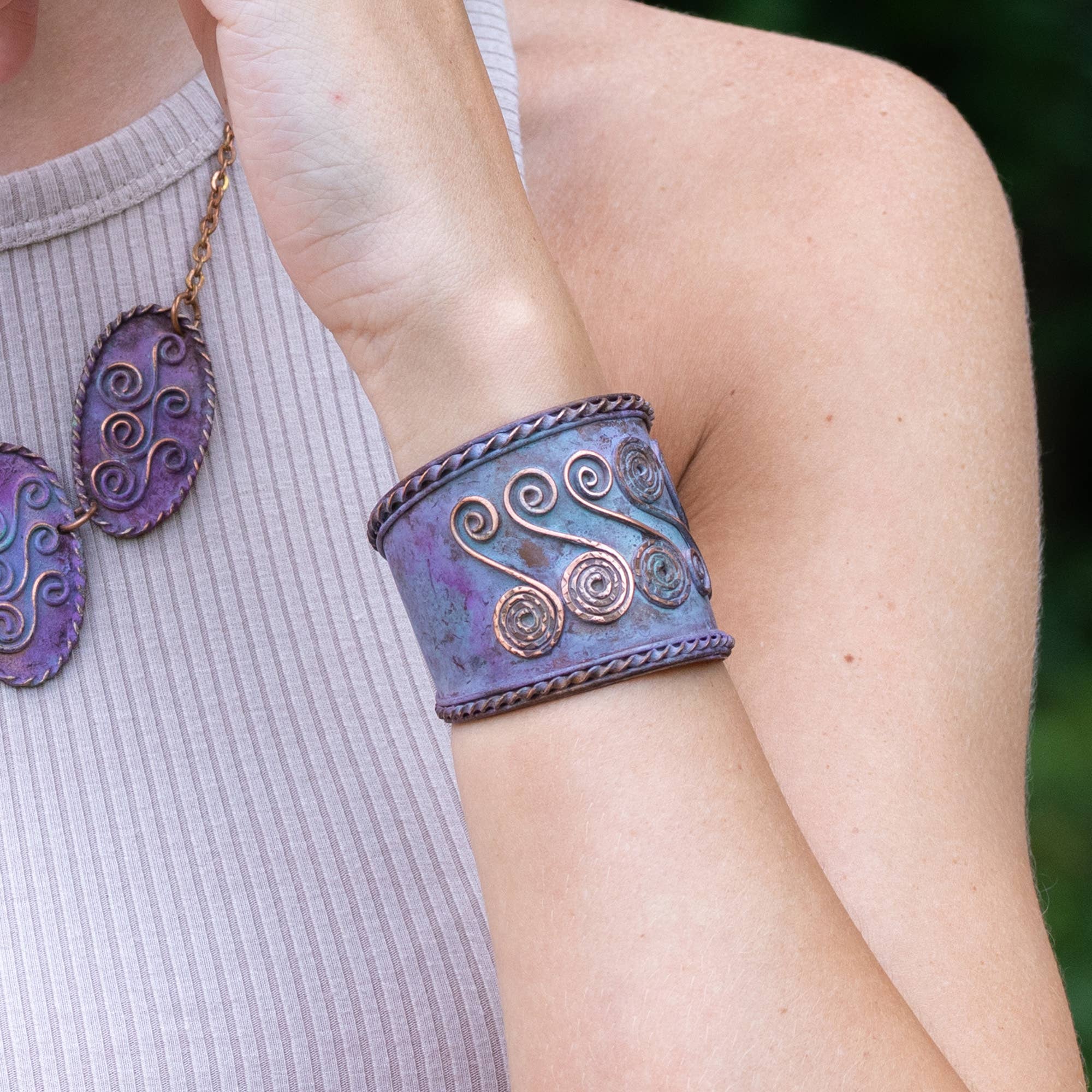 Person wearing a purple and silver bracelet with matching earrings outdoors
