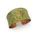 Copper cuff bracelet with green and gold pattern on a white background
