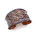 Copper cuff bracelet with intricate designs on a white background