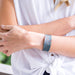 Person wearing a white shirt with a patterned bracelet on a blurred outdoor background