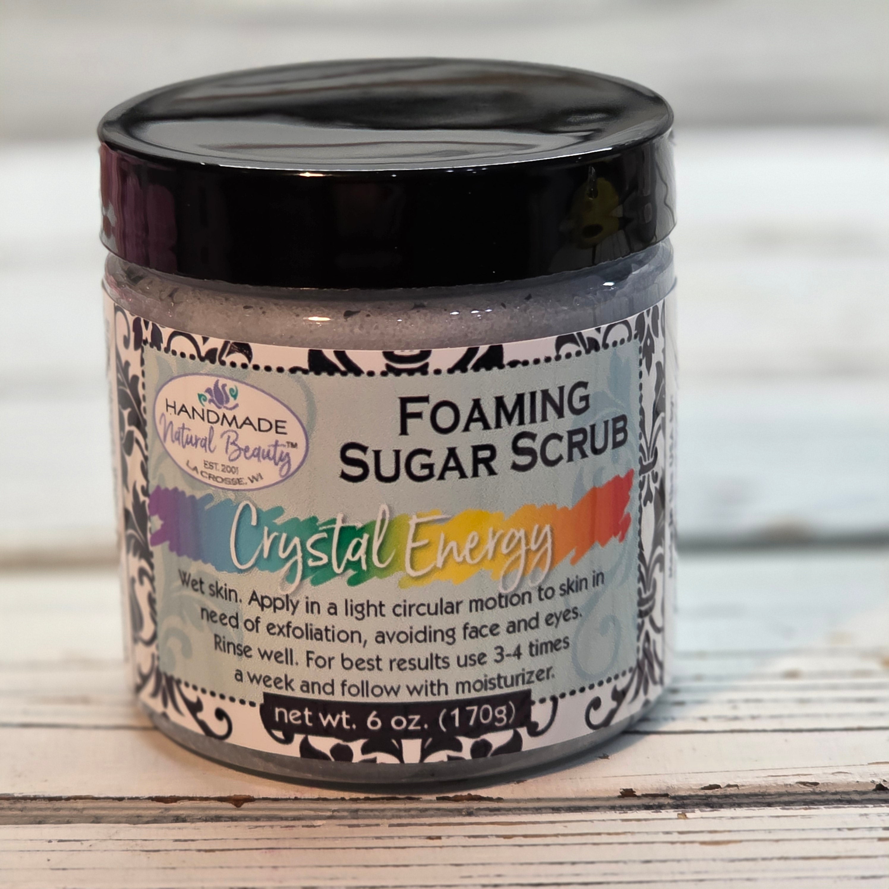 Crystal Energy Foaming sugar scrub container with decorative label on a wooden surface