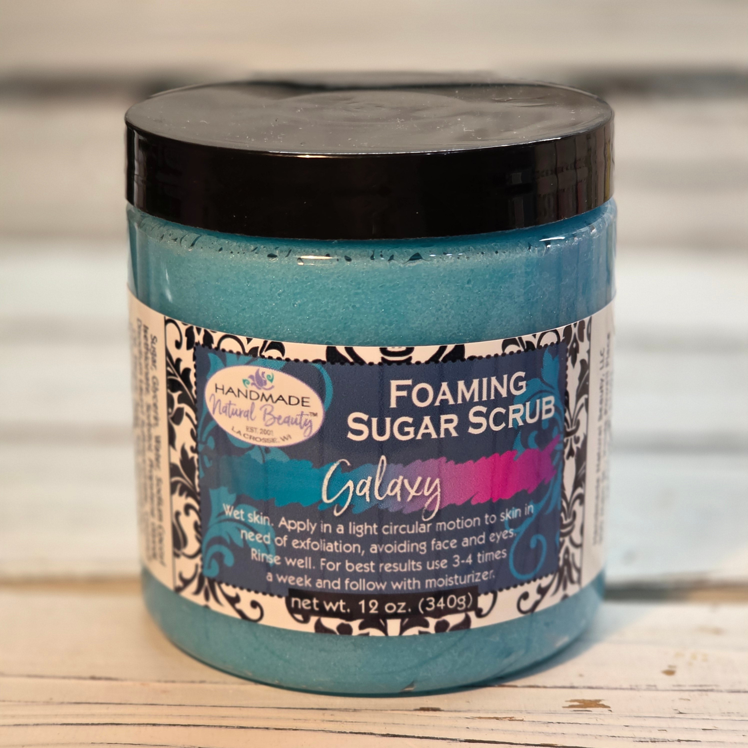 Jar of Galaxy foaming sugar scrub with decorative label by Handmade Natural Beauty on a wooden surface