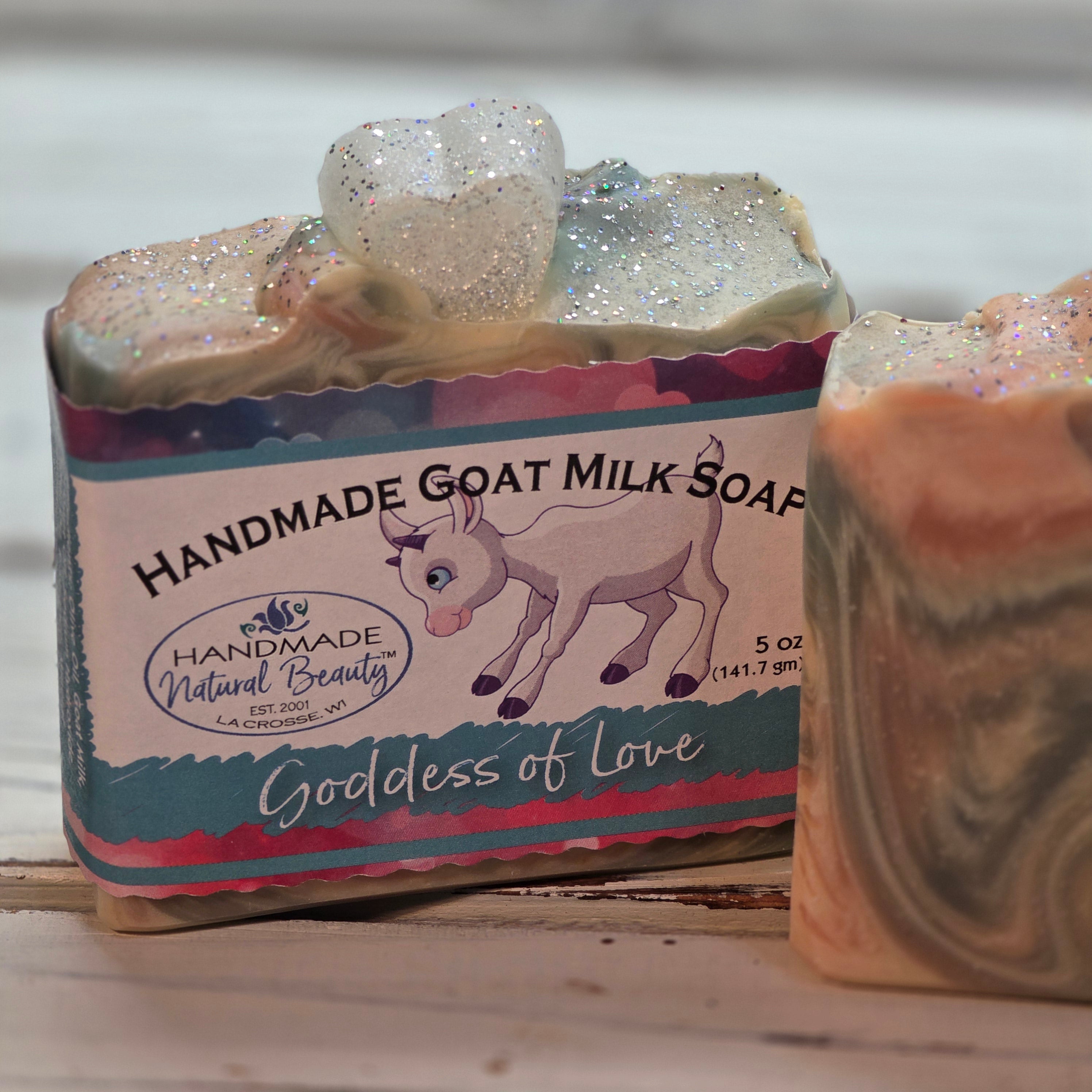 Handmade goat milk soap with a colorful label by Handmade Natural Beauty named 'Goddess of Love' on a wooden surface.