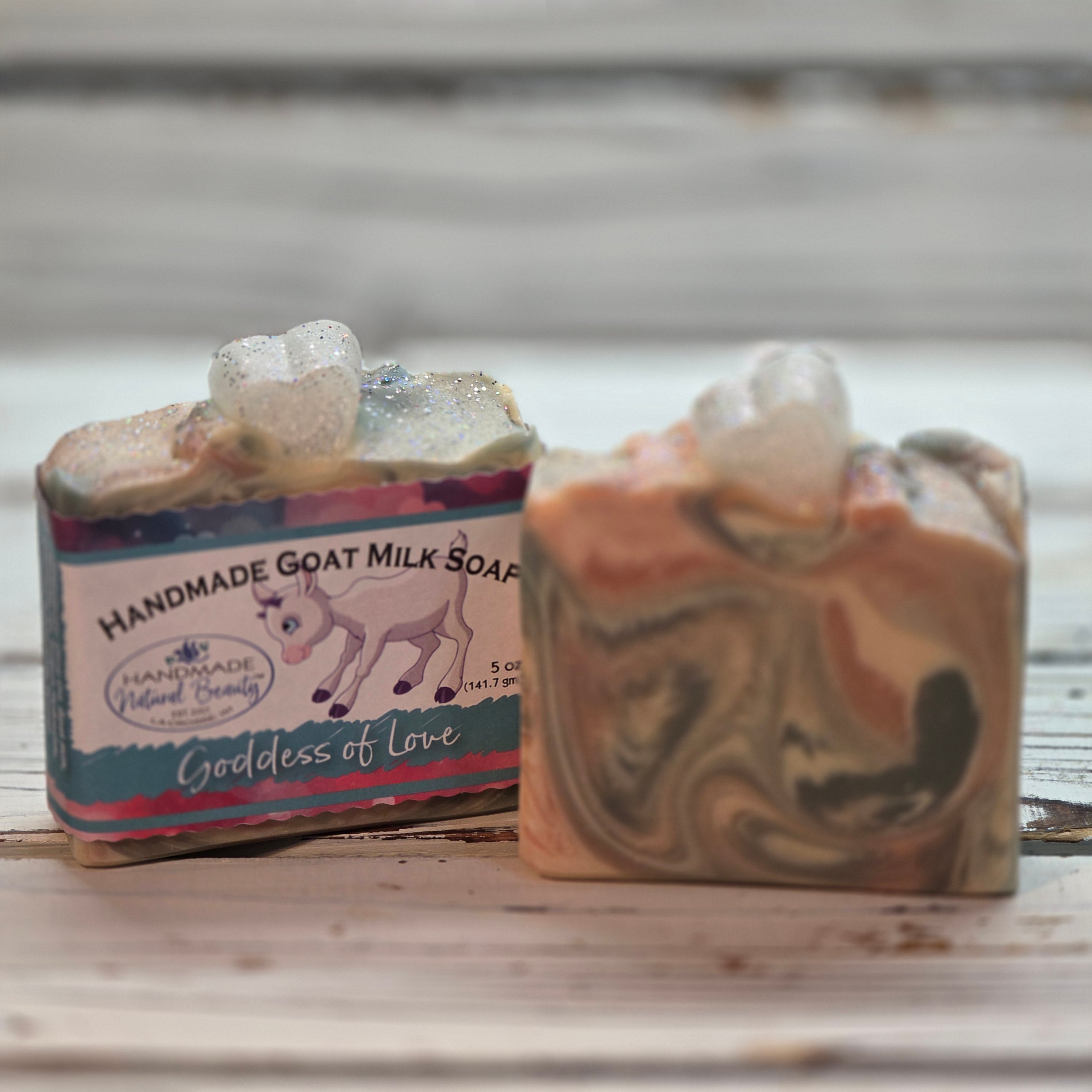 Handmade Goat milk soap by Handmade Natural Beauty labeled Goddess of love. It is a pink blue and white swirled soap with a white glycerin soap heart on top.