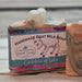 Handmade goat milk soap with a colorful label by Handmade Natural Beauty named 'Goddess of Love' on a wooden surface.