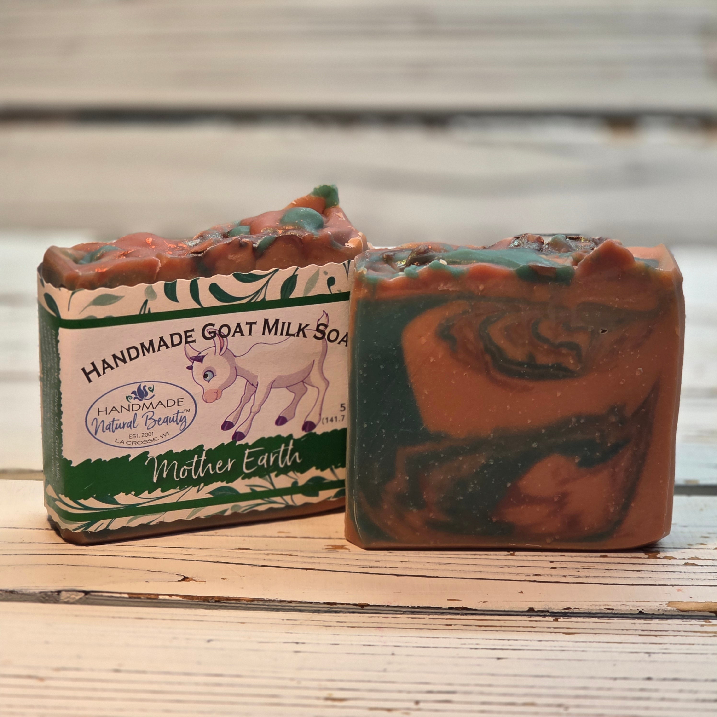 Two bars of handmade goat milk soap with a label on a wooden surface