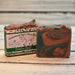 Two bars of handmade goat milk soap with a label on a wooden surface
