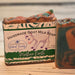 Bar of goat milk soap by Handmade Natural Beauty with 'Mother Earth' packaging on a wooden surface