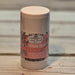Black Rose & Spice Lotion bar in a cylindrical container with a decorative label on a wooden surface.