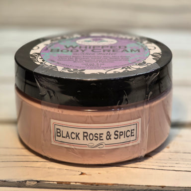 Jar of body cream labeled 'Black Rose & Spice' on a wooden surface.