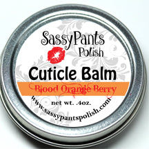 A cuticle balm in a small silver tin, placed on a wooden surface. Blood Orange Berry by Sassy Pants Polish