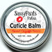 A cuticle balm in a small silver tin, placed on a wooden surface. Blood Orange Berry by Sassy Pants Polish