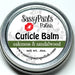 A cuticle balm labeled as Oakmoss & Sandalwood in a small silver metal tin.
