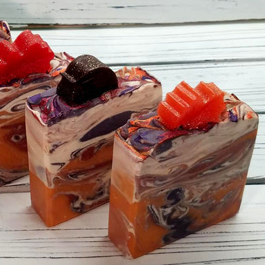 Orange purple and white swirled goat milk soap by Handmade Natural Beauty featuring various shapes of autumn leaves glycerin soaps on top.