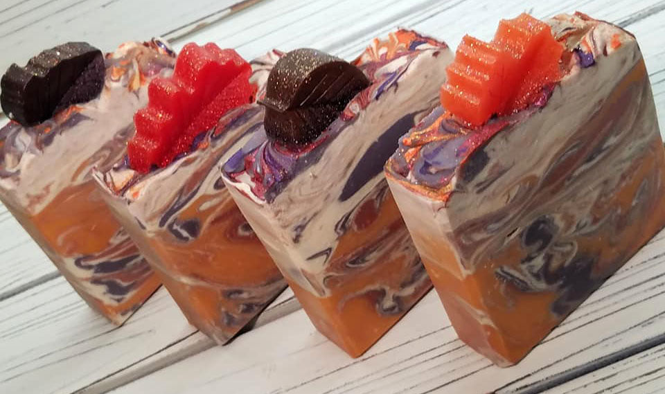 Orange purple and white swirled goat milk soap by Handmade Natural Beauty featuring various shapes of autumn leaves glycerin soaps on top.