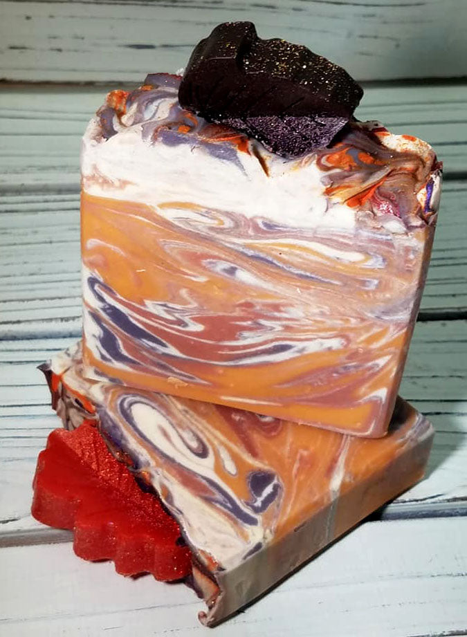 Orange purple and white swirled goat milk soap by Handmade Natural Beauty featuring various shapes of autumn leaves glycerin soaps on top.