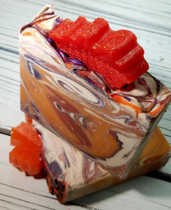 Orange purple and white swirled goat milk soap by Handmade Natural Beauty featuring various shapes of autumn leaves glycerin soaps on top.