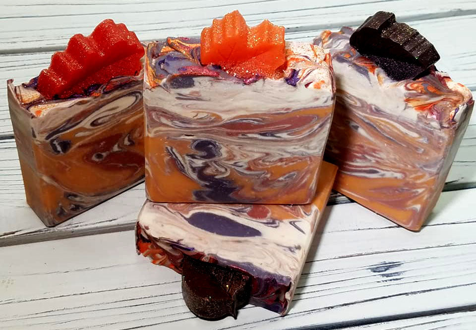 Orange purple and white swirled goat milk soap by Handmade Natural Beauty featuring various shapes of autumn leaves glycerin soaps on top.