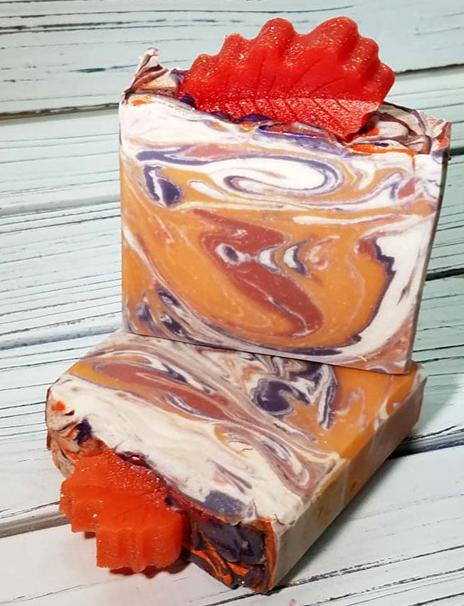 Orange purple and white swirled goat milk soap by Handmade Natural Beauty featuring various shapes of autumn leaves glycerin soaps on top.