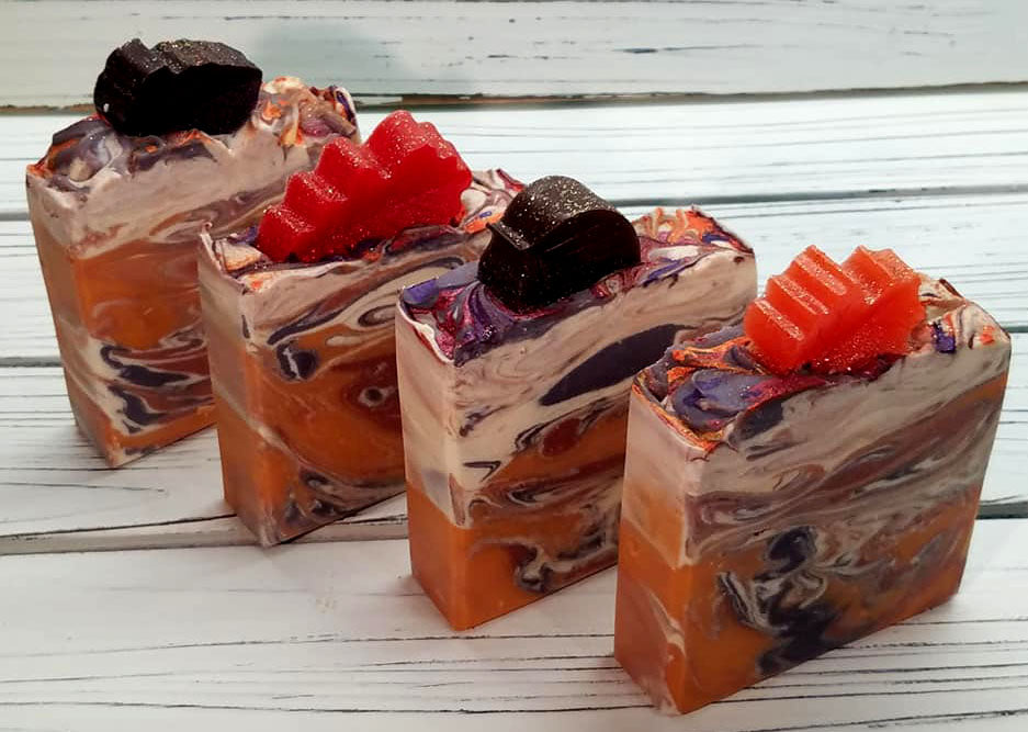 Orange purple and white swirled goat milk soap by Handmade Natural Beauty featuring various shapes of autumn leaves glycerin soaps on top.